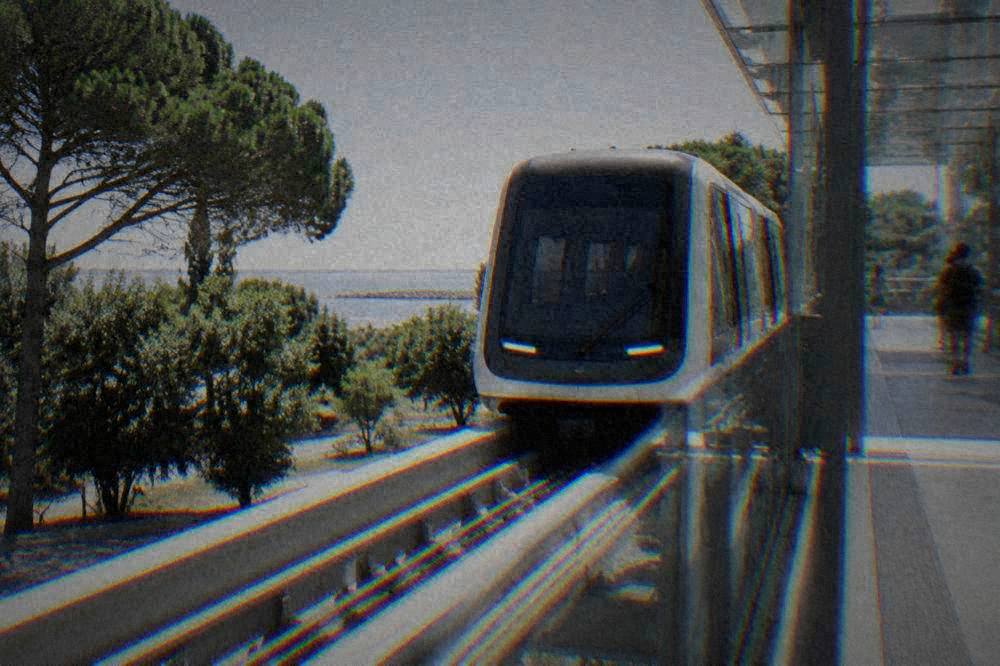 An elevated driverless people mover vehicle arriving at a glass station platform