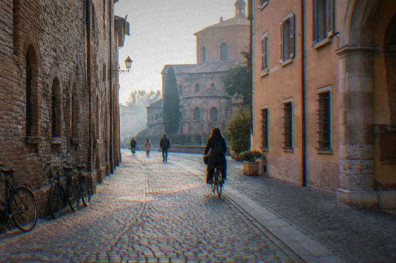 A quiet cobbled street in central Ravenna with bicycles leaning against a stone wall