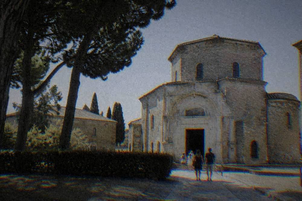 A stone monument exterior in Ravenna under a clear sky with visitors at the entrance
