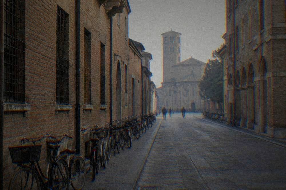 A flat city street in Ravenna lined with bicycles and old brick facades leading toward the historic centre
