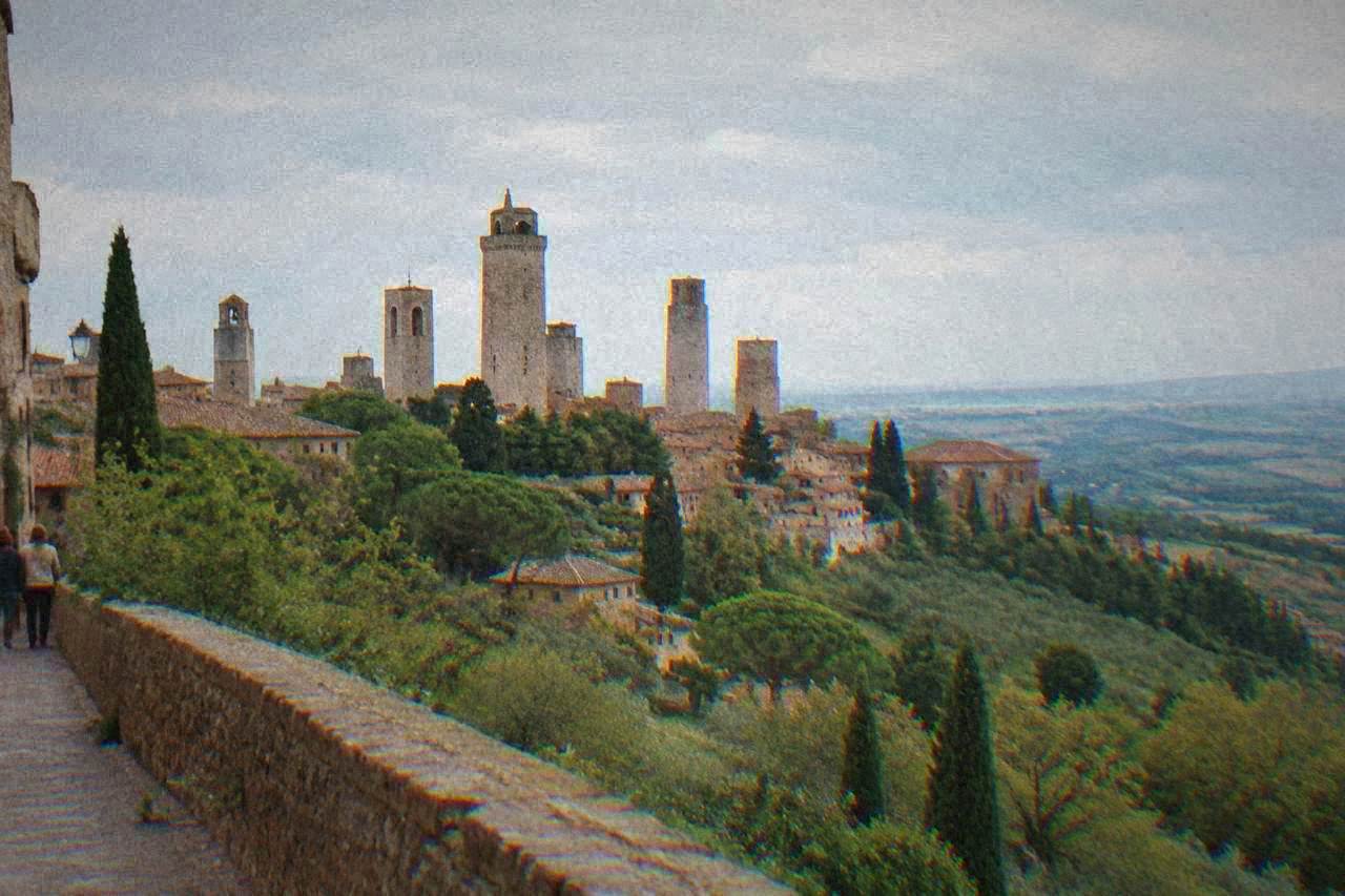 A hilltop old town with stone towers rising above rolling countryside on a clear day