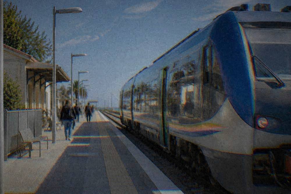 A regional train waiting at a small Italian station platform in morning light