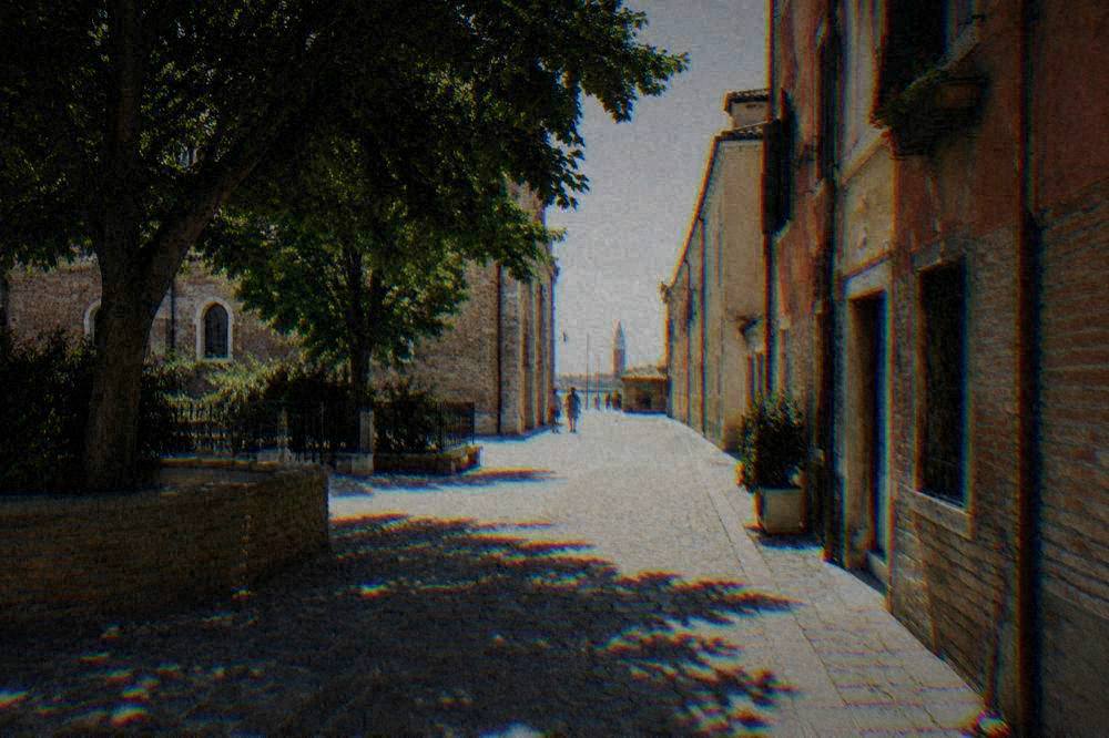 A quiet street in Ravenna with cyclists and old brick buildings in warm light