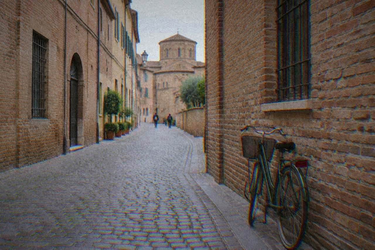 A quiet cobbled street in the historic centre of Ravenna with brick facades and a bicycle leaning against a wall