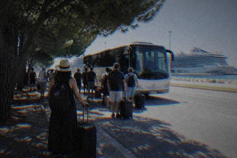 Passengers with luggage waiting beside a shuttle bus at the Porto Corsini cruise terminal
