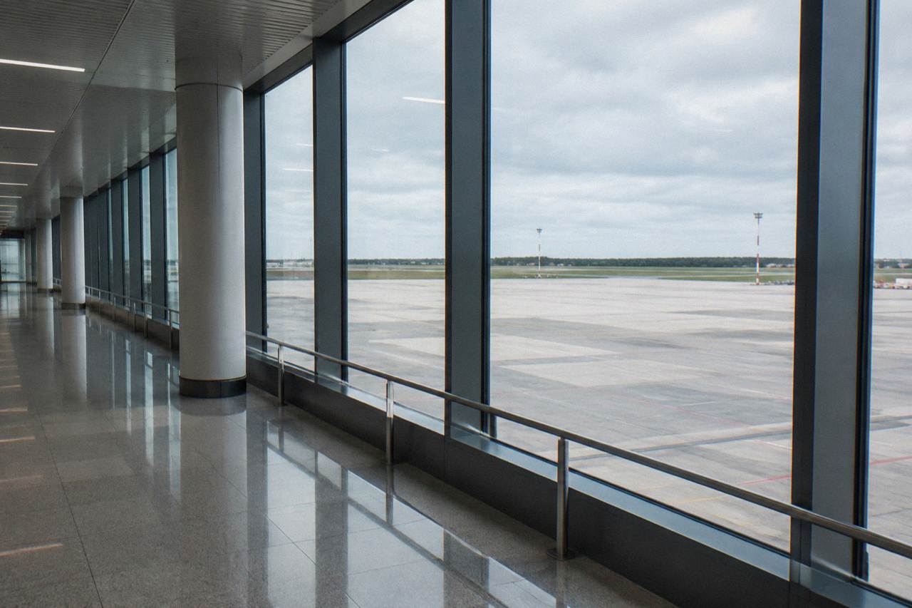A passenger walking with a suitcase through a modern airport terminal corridor