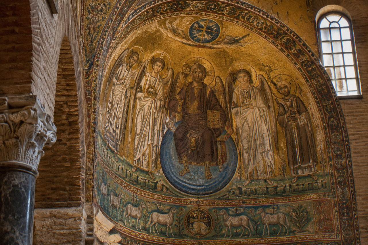 Gold Byzantine mosaic figures glowing inside an ancient brick church interior in Ravenna
