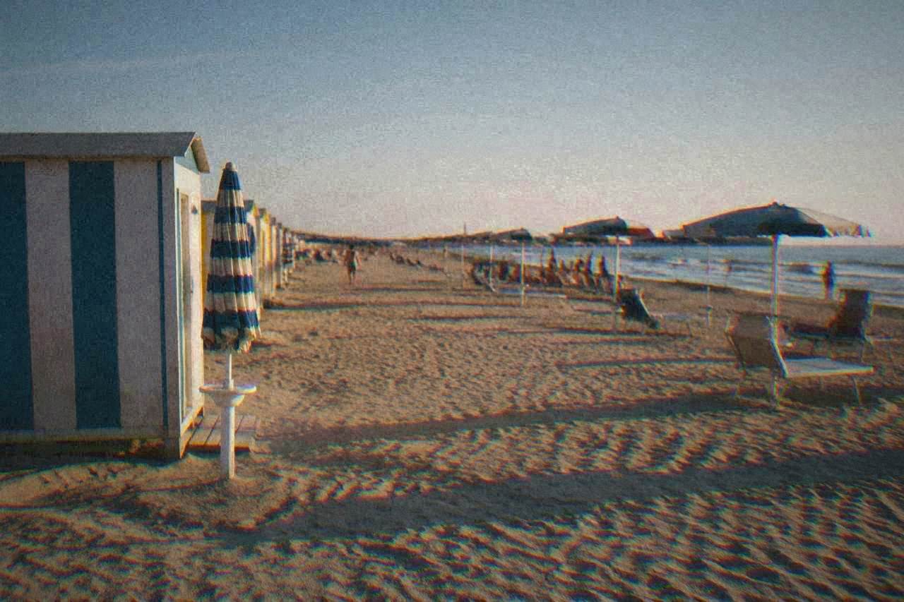 A wide sandy Adriatic beach with rows of umbrellas and bathing huts at an Italian seaside resort