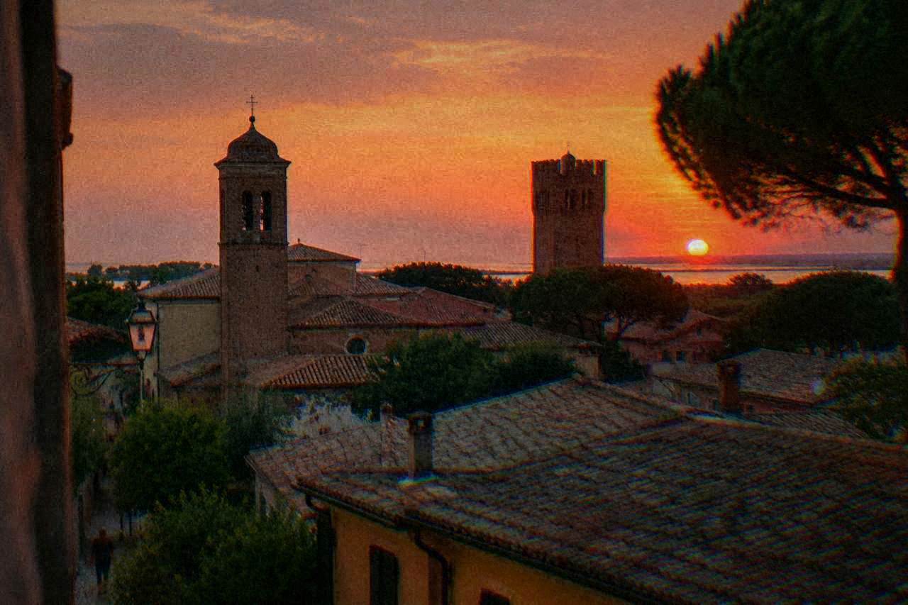 Evening view over tiled rooftops and brick towers of a small Italian historic centre