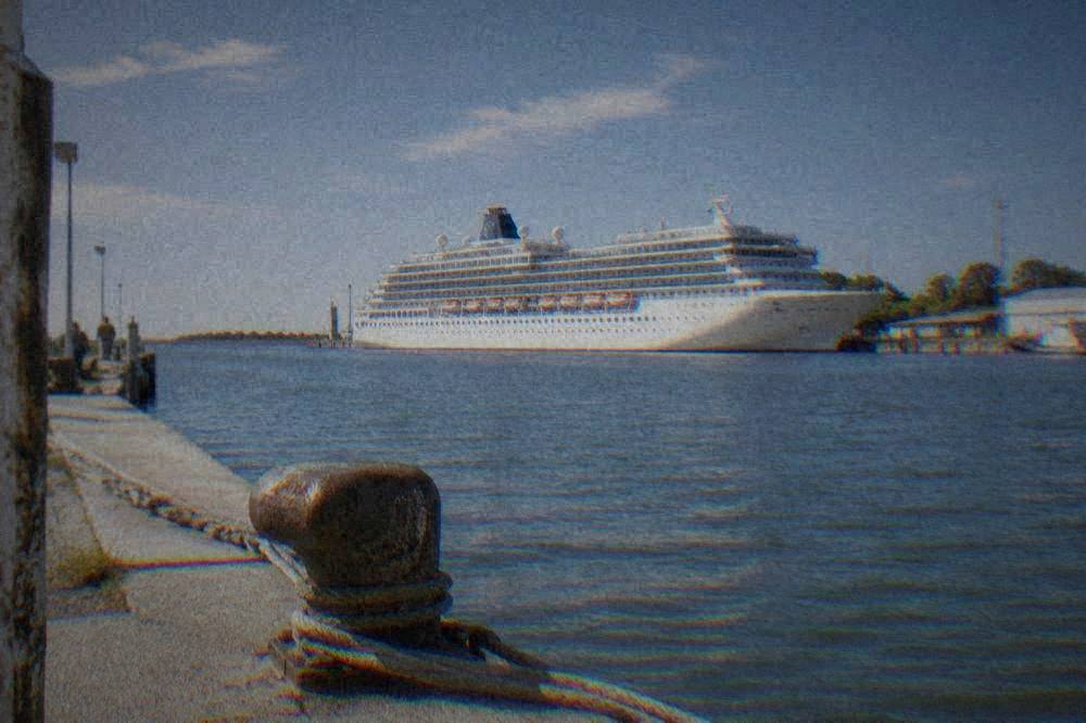 A moored cruise ship seen across the water from a canal-side berth
