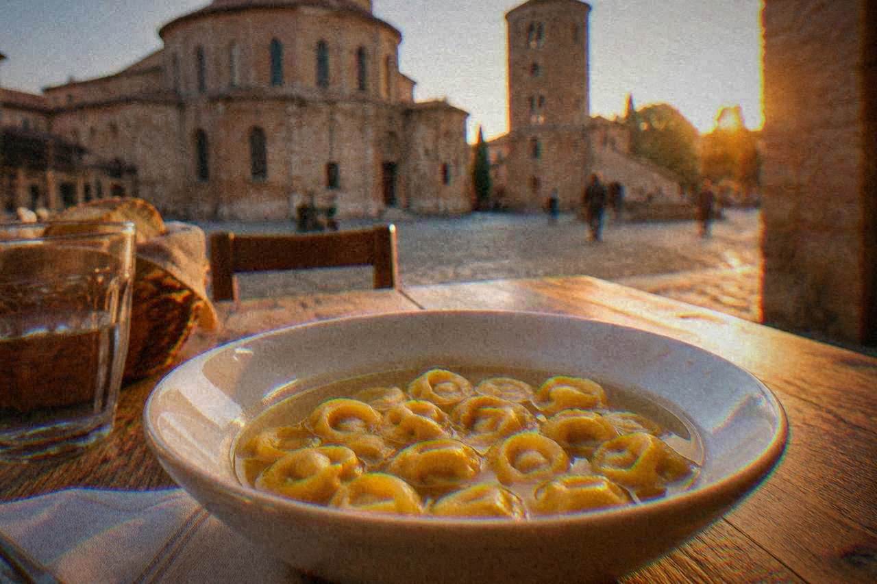 Small ring-shaped stuffed pasta called cappelletti served in a bowl of golden broth on a rustic table