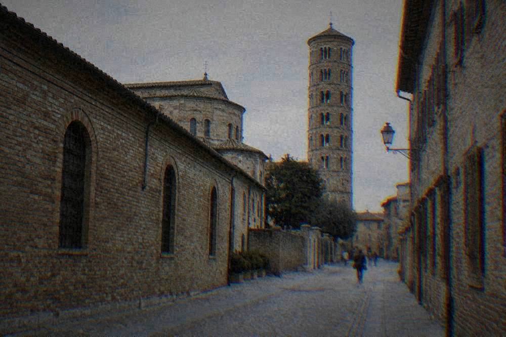 A quiet Ravenna street of brick facades and a bell tower in late afternoon light