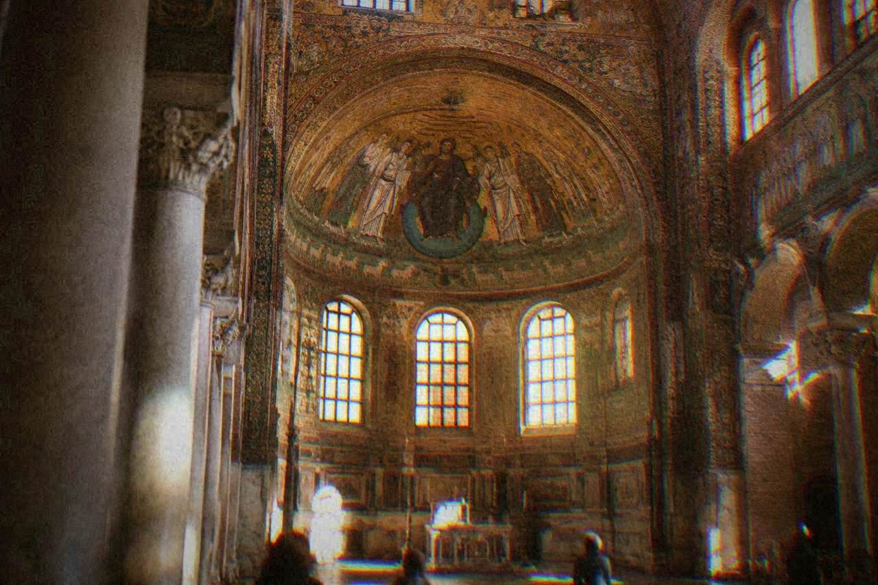 Interior of the Basilica of San Vitale in Ravenna with golden mosaic decoration in the apse and choir under daylight from the windows