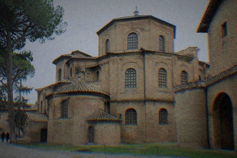Exterior brickwork of the Basilica of San Vitale in Ravenna under a clear sky, showing the octagonal shape and simple brick facade