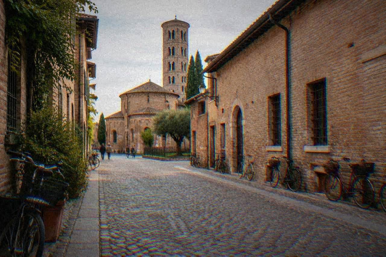 A quiet cobbled street in central Ravenna lined with low brick buildings and bicycles
