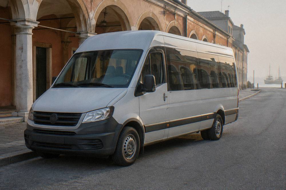 A shuttle bus parked on a quiet street beside a historic Italian arcade