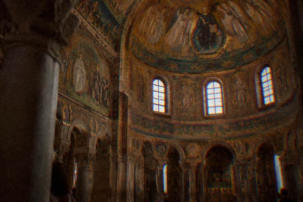 Golden Byzantine mosaics inside an ancient Ravenna church, lit softly under a domed ceiling