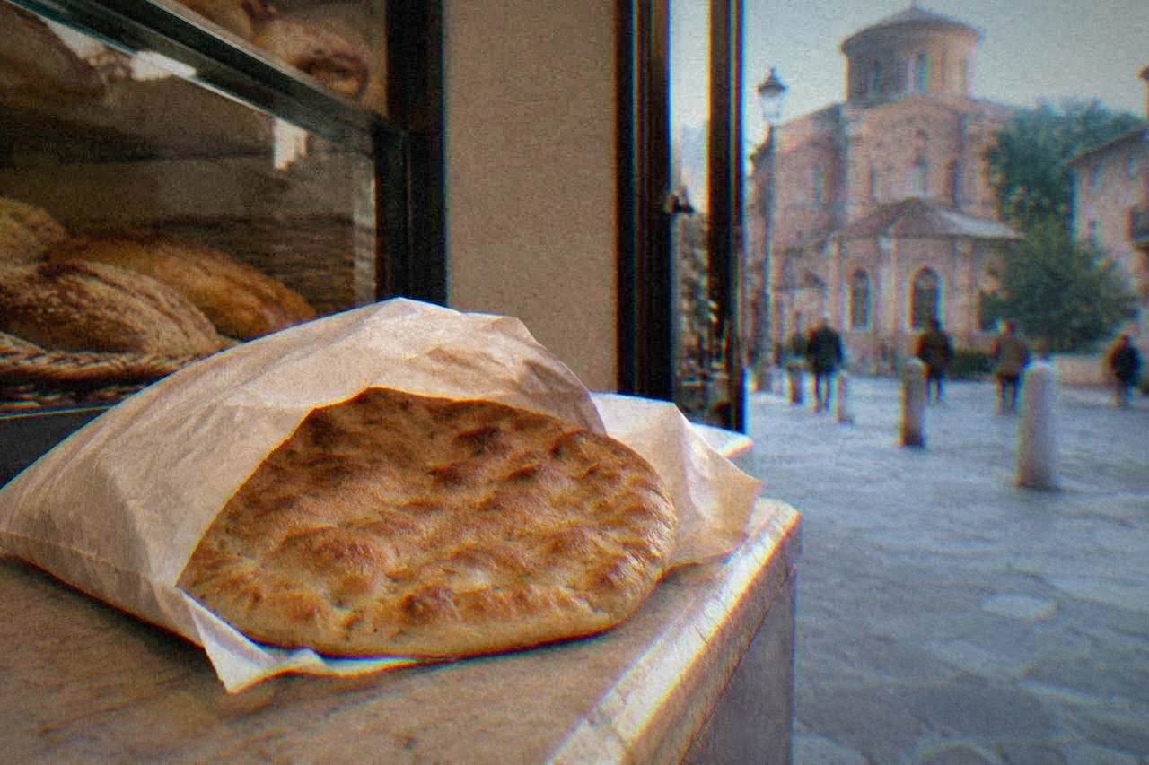 A freshly cooked round flatbread wrapped in paper on a bakery counter