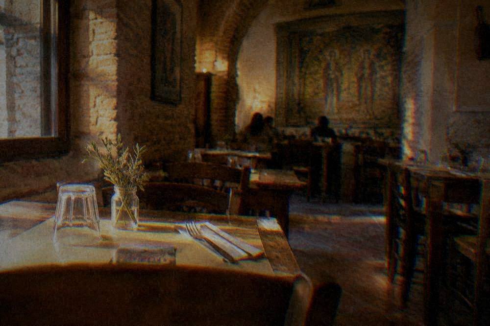 An osteria interior in Ravenna with simple wooden tables, paper placemats and a small printed menu