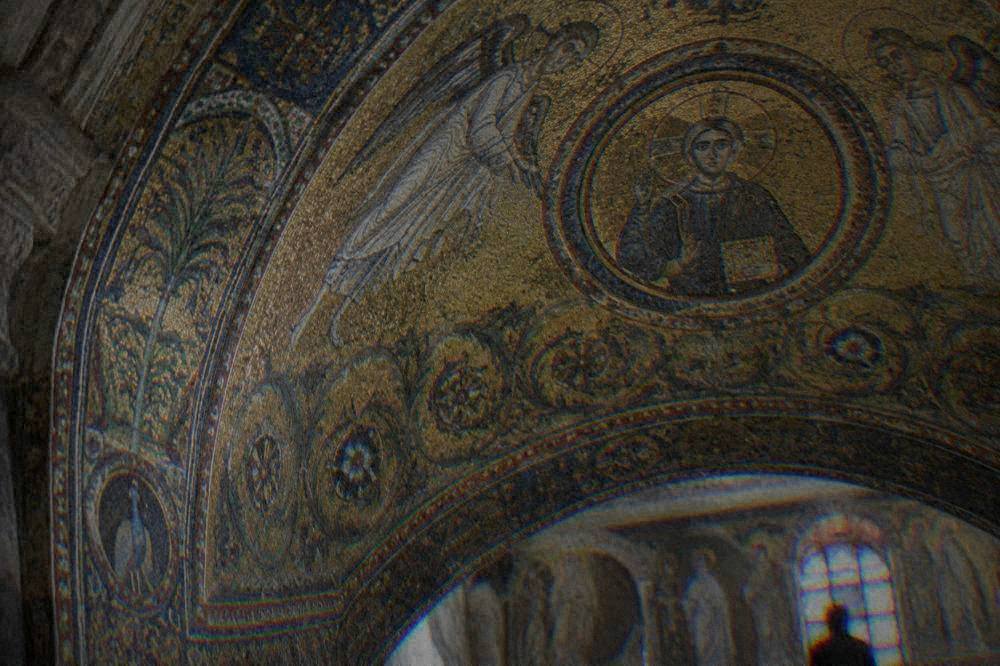 A close view of a gold mosaic vault showing figures and decorative patterns in glass tiles