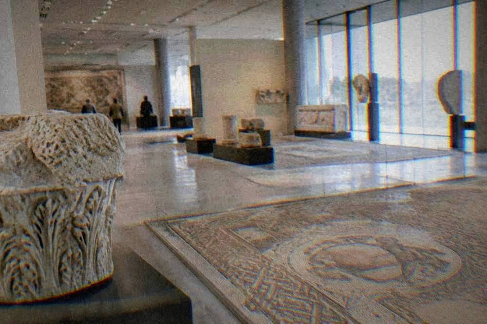 A modern museum interior with ancient stone fragments and floor mosaics under bright lighting