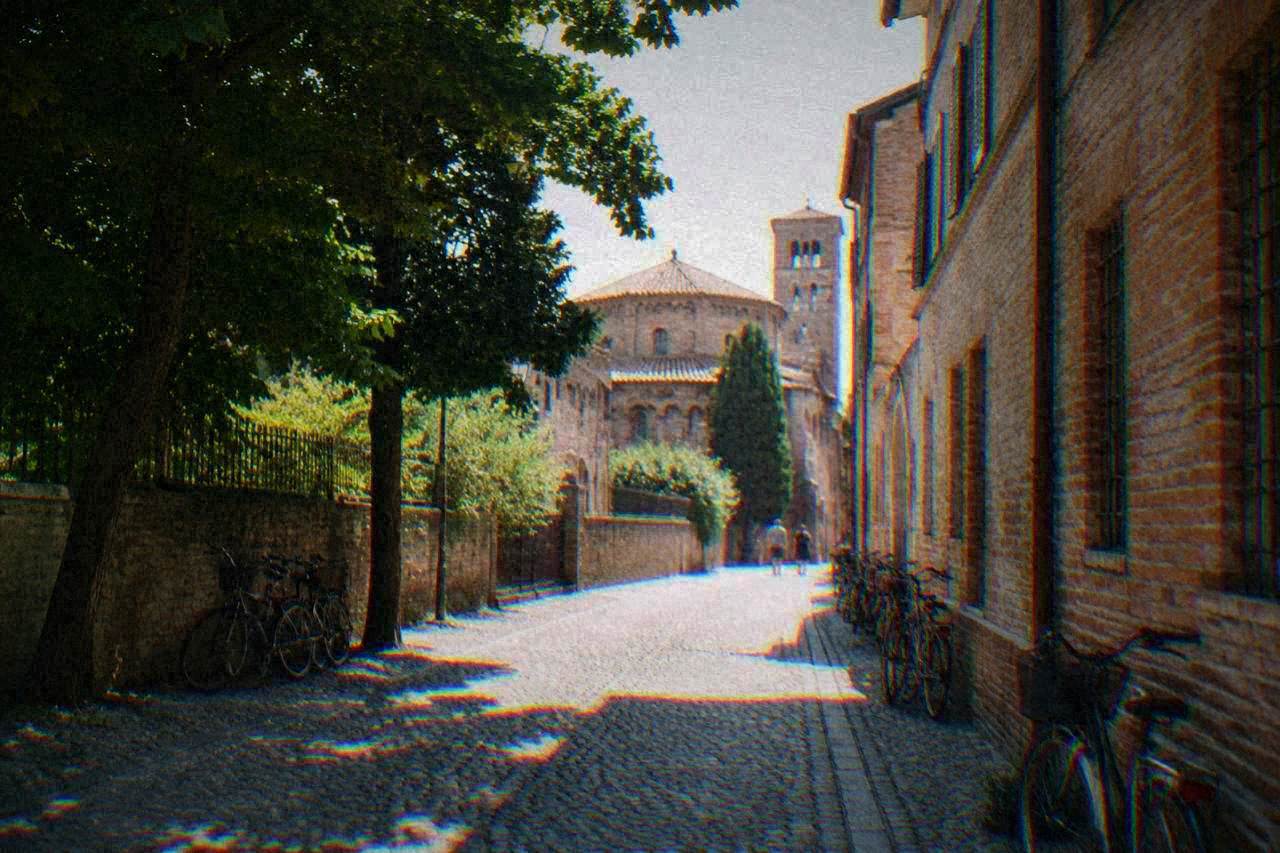 A quiet cobbled street in the historic centre of Ravenna lined with brick buildings and bicycles