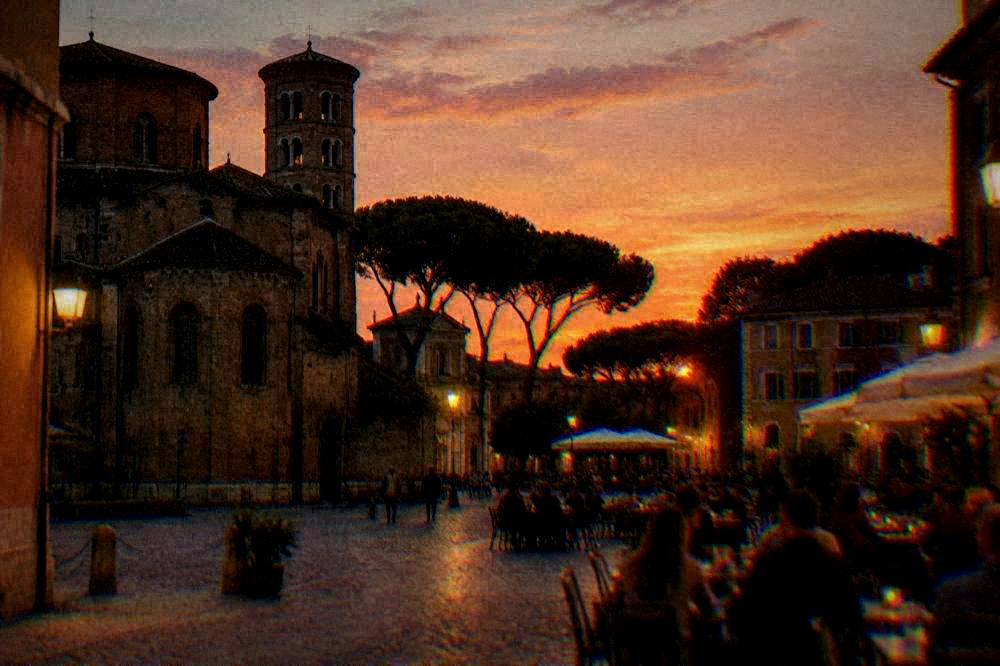 An evening square in Ravenna with warm street lighting and people at outdoor tables
