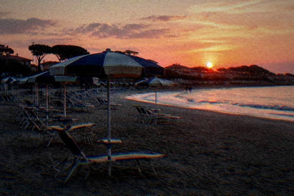 Empty beach chairs under parasols in early evening light on an autumn shore