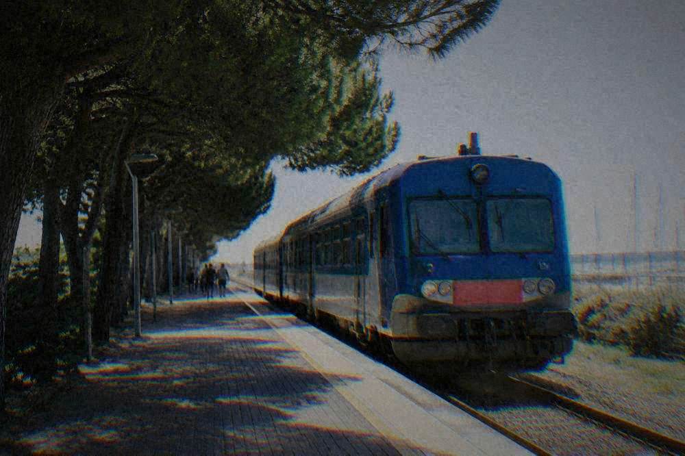 Blue regional train waiting at a small Italian railway station platform