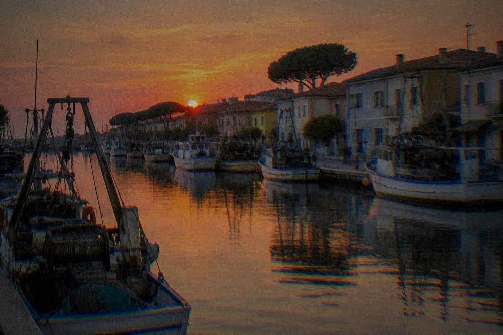 Harbour canal with moored fishing boats and pastel buildings at dusk