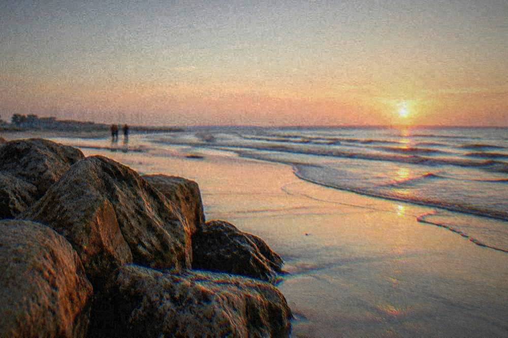 A calm Adriatic shoreline at dawn with wet sand reflecting a pale sky