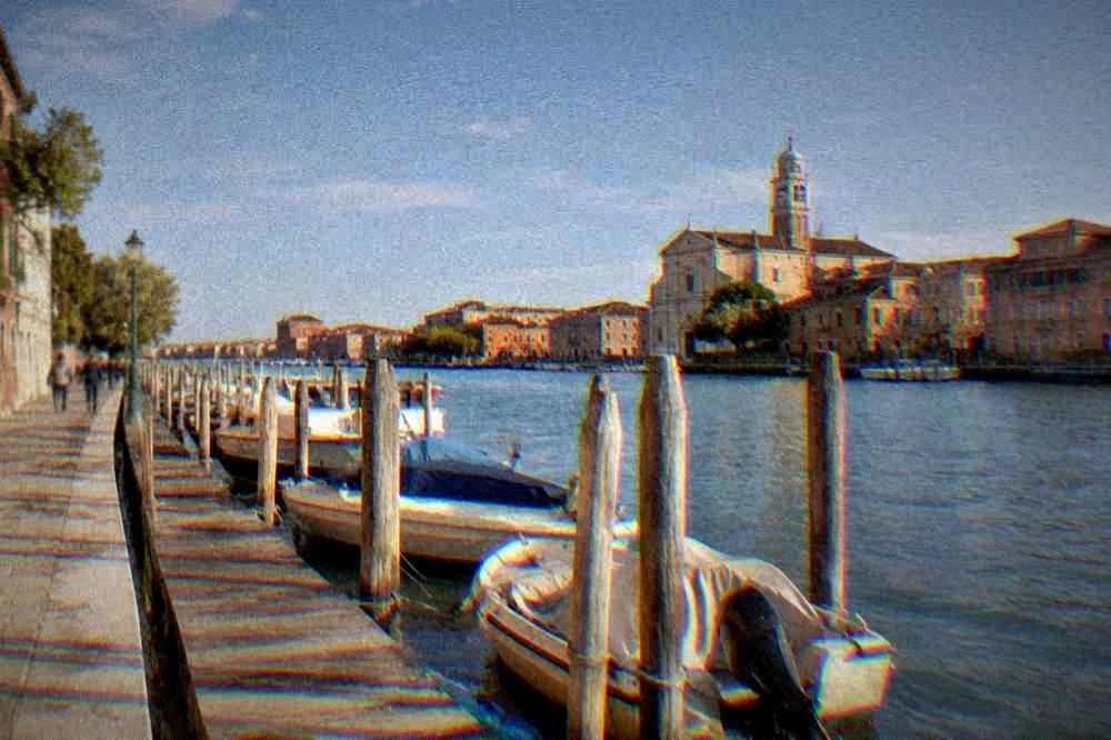 A marina canal with small boats moored along a wooden jetty at golden hour