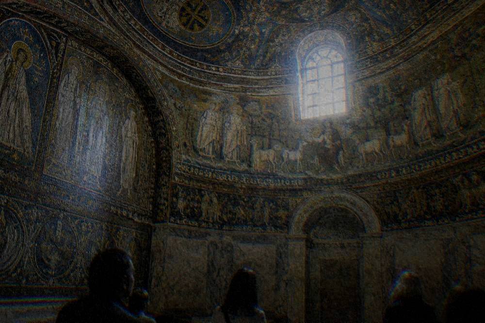 Visitors standing quietly in a small mosaic chamber looking upward
