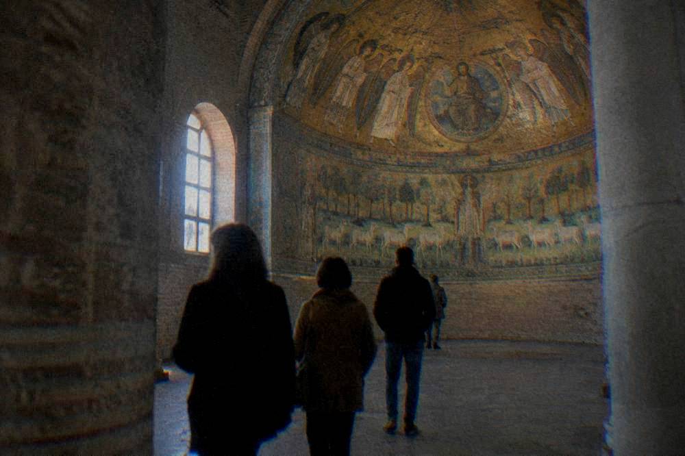 A guide speaking to a small group in front of an ancient mosaic in Ravenna