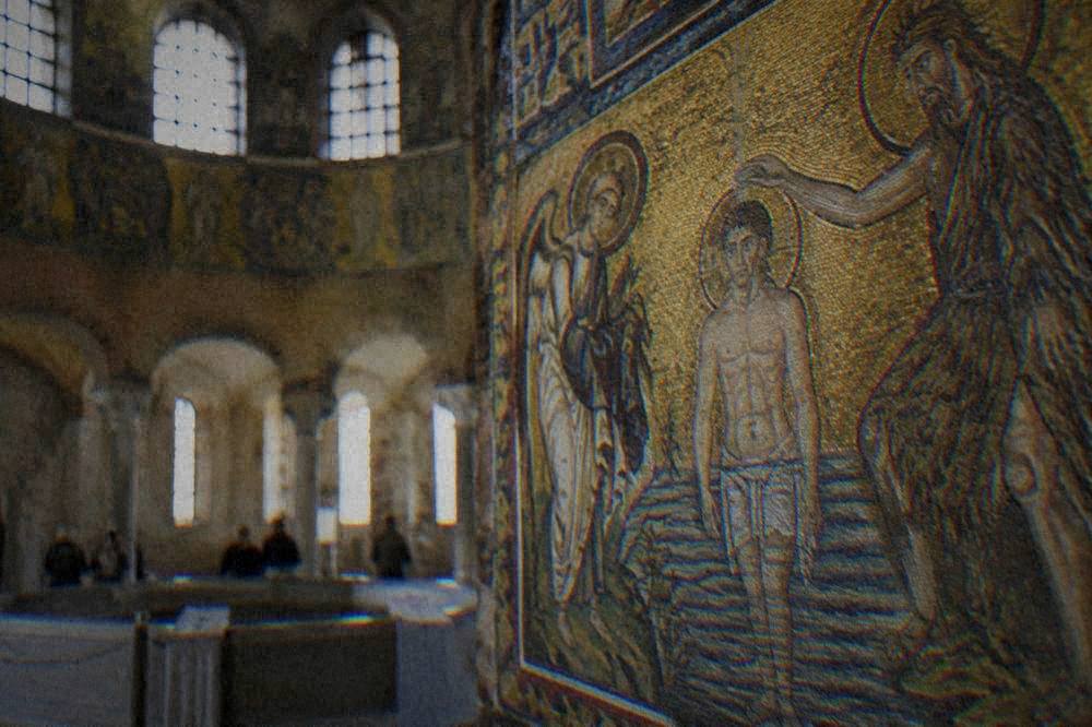 Gold mosaic detail of a beardless figure being baptised in a river