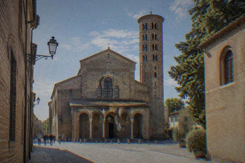 Sunlit street in Ravenna's historic centre with the basilica and old brick buildings