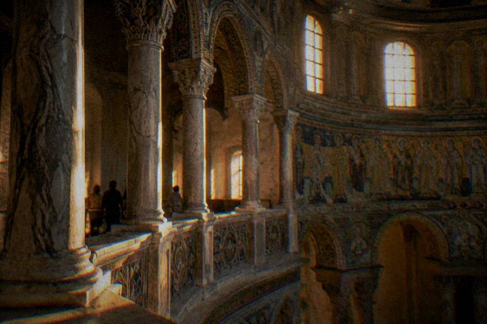 Marble columns and mosaic details along the gallery level inside San Vitale