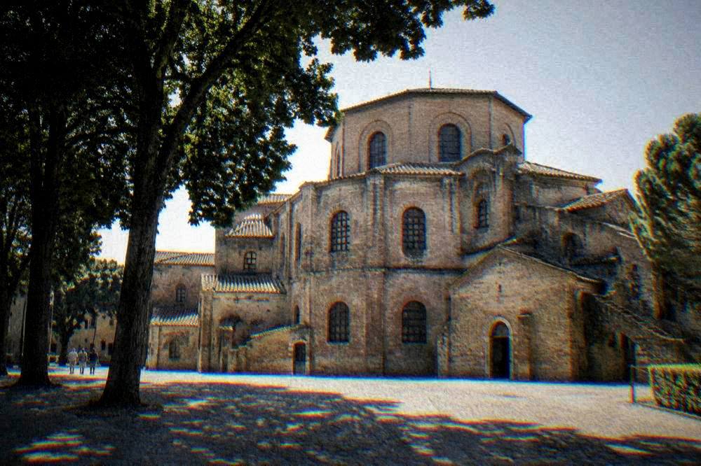 The brick exterior of the Basilica of San Vitale seen from the adjacent piazza