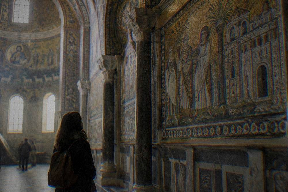 A visitor reading the mosaic panels inside the Basilica of San Vitale