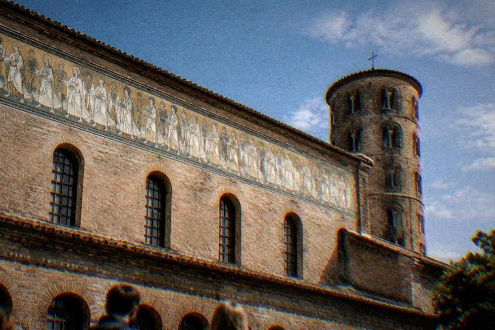 A procession of white-robed figures in a mosaic band along the upper wall of a basilica