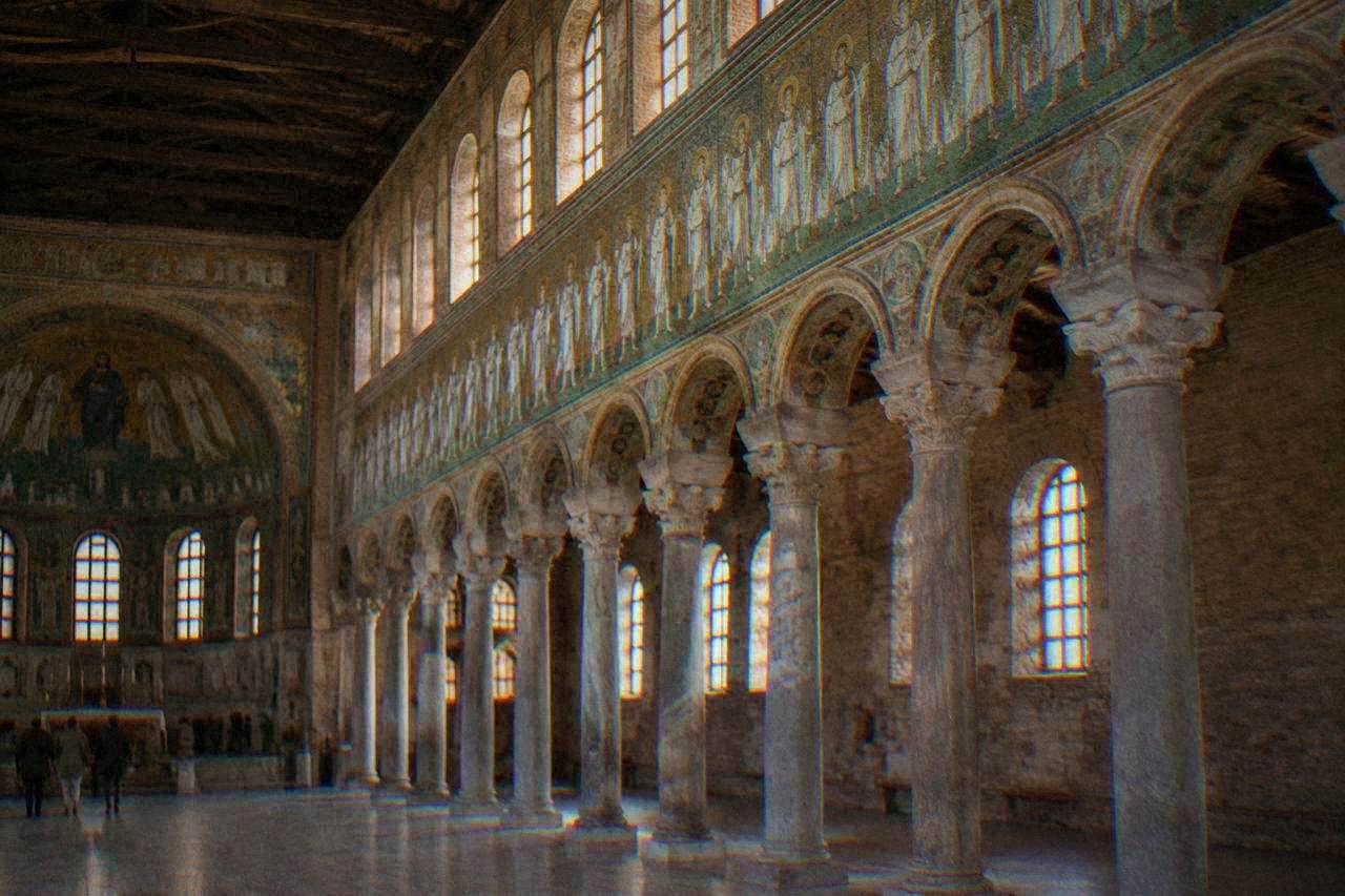 Interior of a basilica in Ravenna with a row of columns and mosaic-covered walls above them