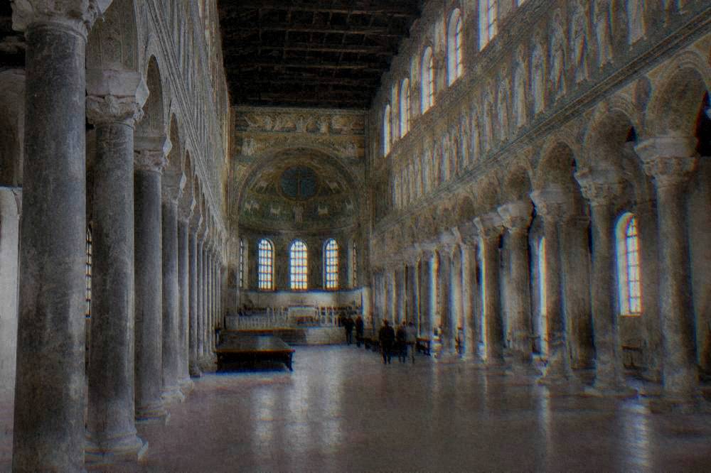 Sunlit nave of a basilica with columns on both sides and mosaic bands above