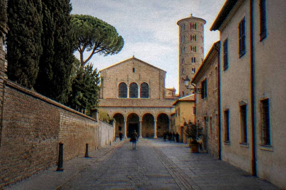 Straight street in a flat Italian city with a brick basilica facade ahead