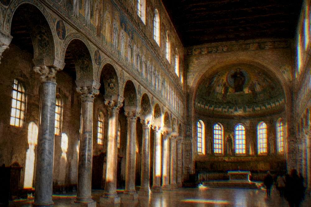 Wide view of a basilica interior with a marble colonnade and a mosaic frieze running to the apse