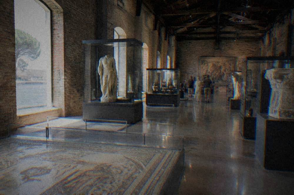 A high exhibition hall inside a converted factory with brick walls and artefacts in glass cases
