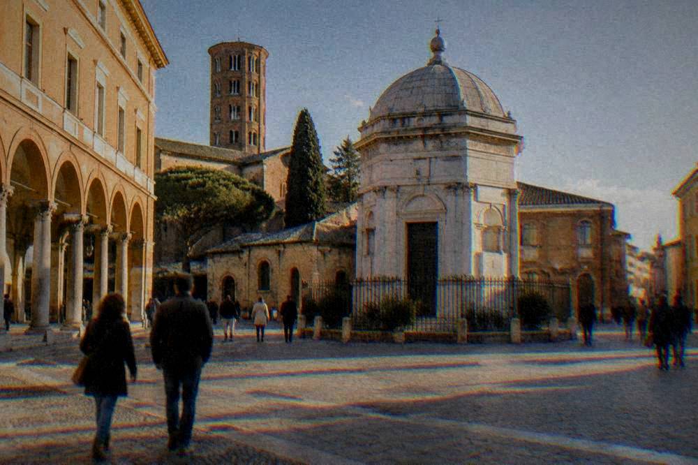 A bright Italian piazza with civic buildings, arcades and people walking