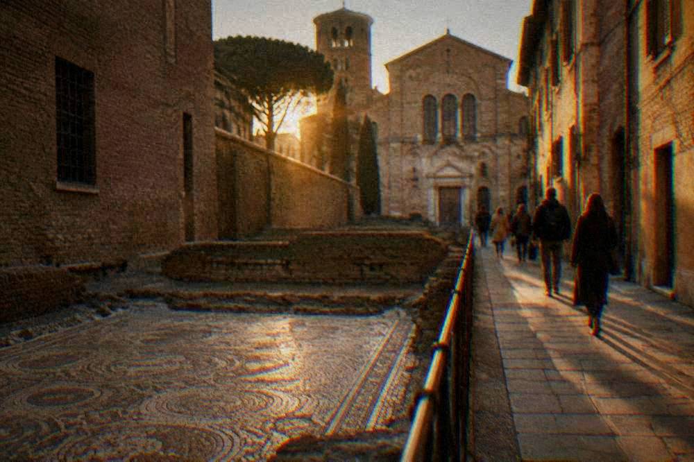 Visitors walking through a narrow old town street toward a church facade in Ravenna