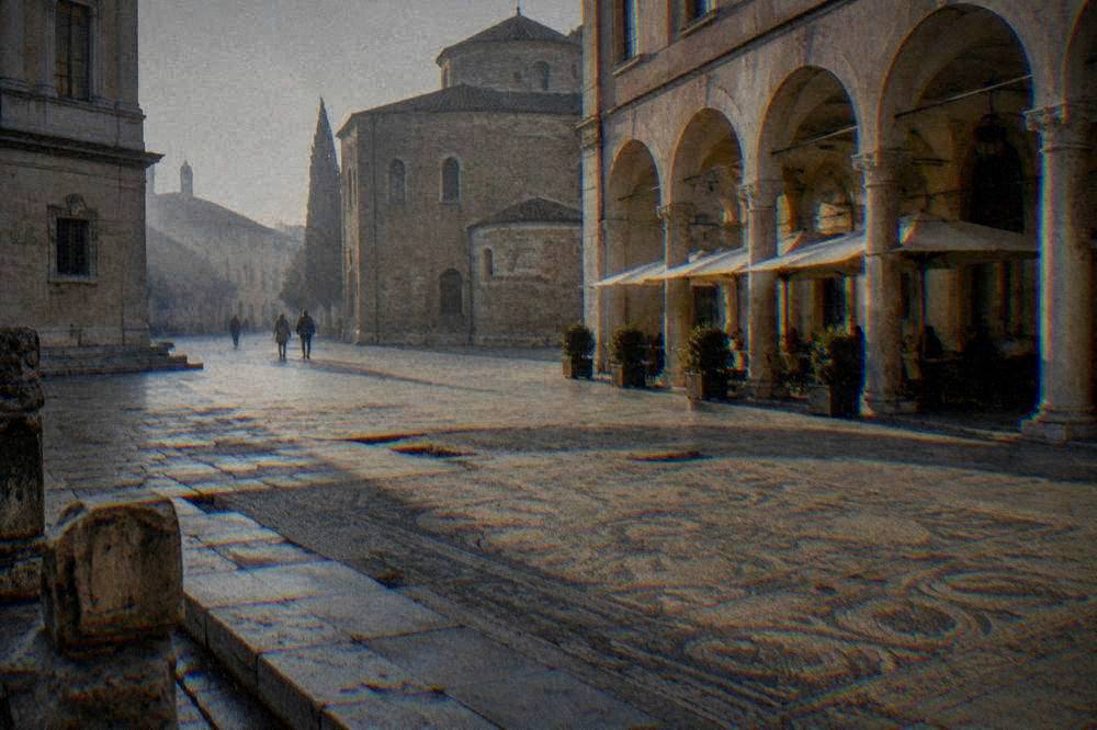 A quiet old square in Ravenna with pale stone buildings and a café under arcades