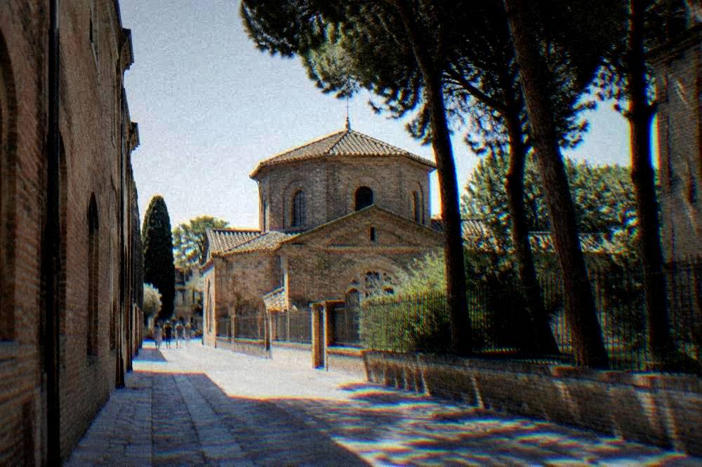 A quiet Ravenna street lined with brick buildings leading toward the monument quarter
