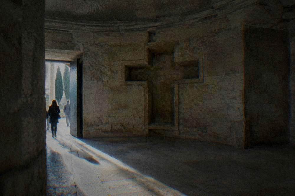 The plain stone interior of the lower chamber with its cruciform niche lit from the doorway